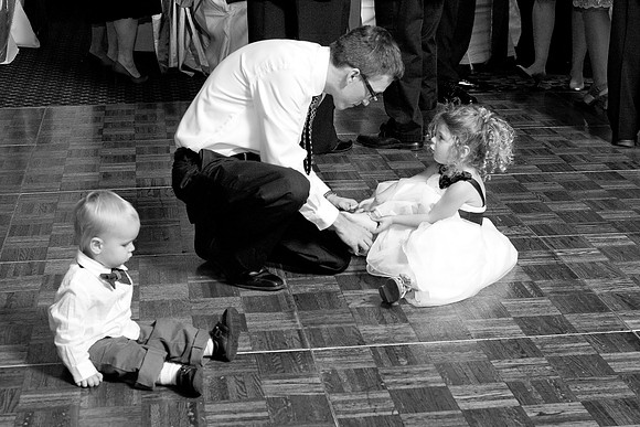 Dad helps daughter tie shoe at wedding candid moment