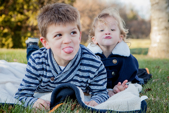 Kids stick tongue out at photographer in park